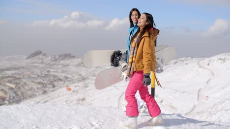 Two-women-carrying-their-snowboards-on-a-mountain