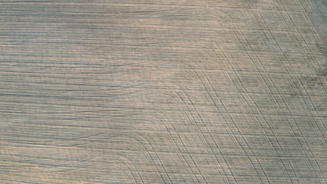 체코 공화국에서 대칭적인 휠 트레일 패턴으로 수확 후 마른 갈색 농작물과 들판의 오버헤드 공중 전망