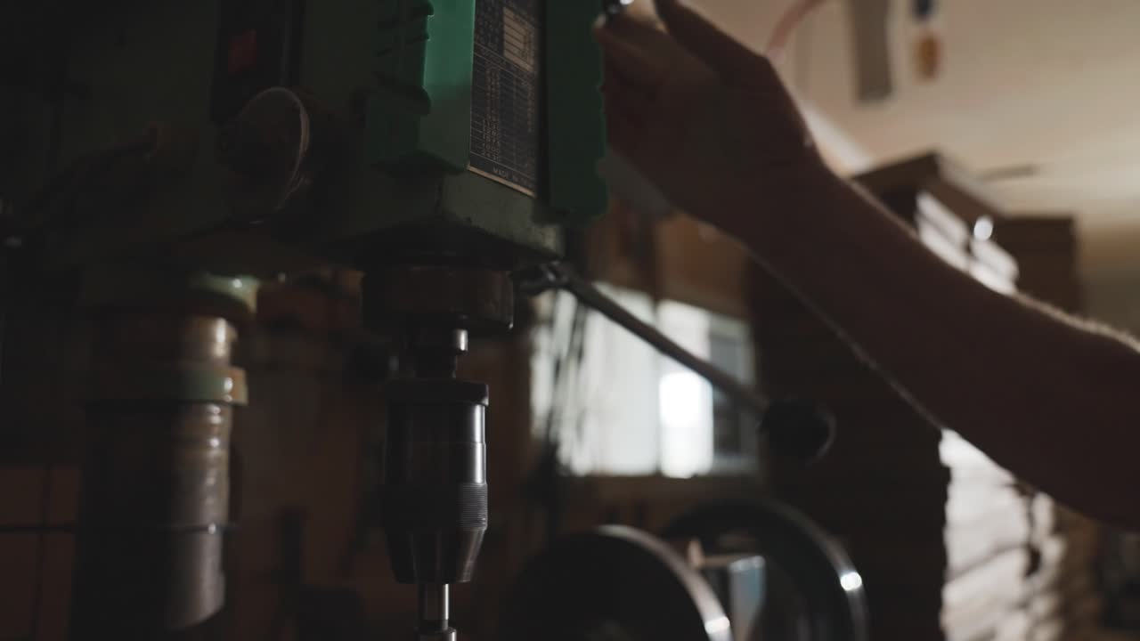 Craftsman using speed handle on milling machine in workshop, up and down