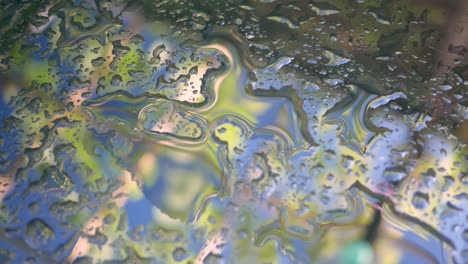 truck shot of a glass table surface covered with raindrops with a blurry reflection of the blue sky