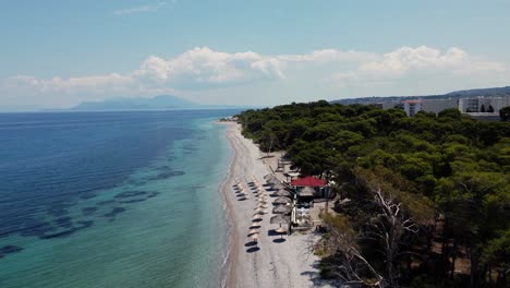 Vista-Aérea-De-La-Playa-De-Arena-Blanca-Y-Mar-Turquesa-En-Un-Centro-Turístico-En-Xylokastro,-Grecia