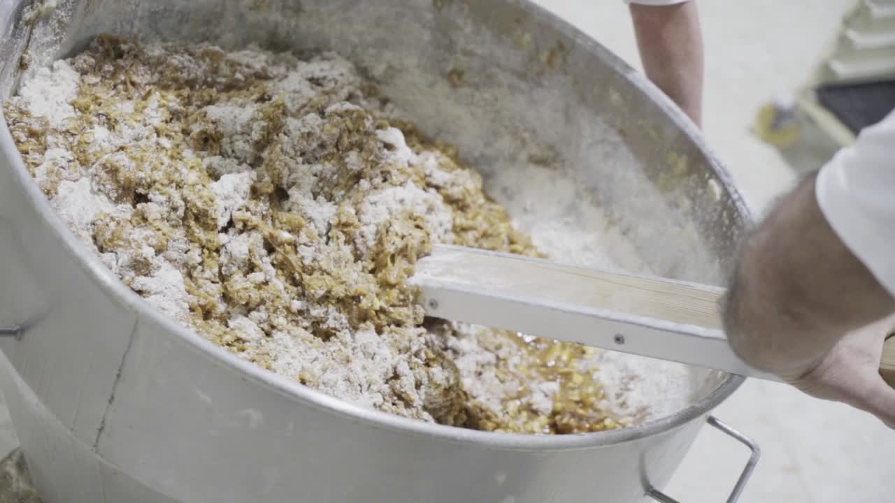 사탕 공장에서 제빵사가 사탕을 섞는 반죽 덩어리의 느린 동작 핸드헬드 샷