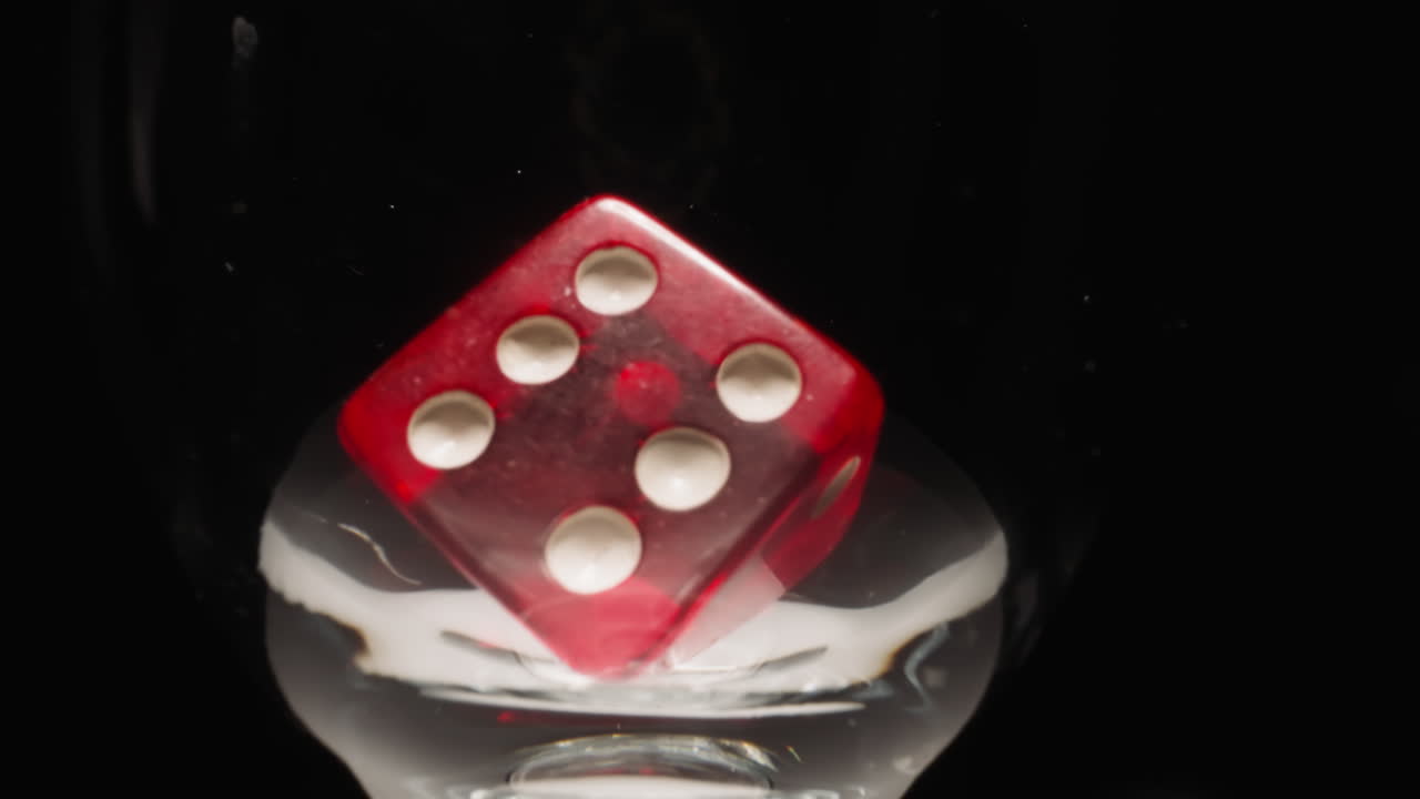 cubo de juego rojo con puntos blancos flotando en vidrio transparente