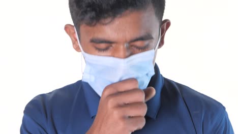 man coughing while wearing a face mask