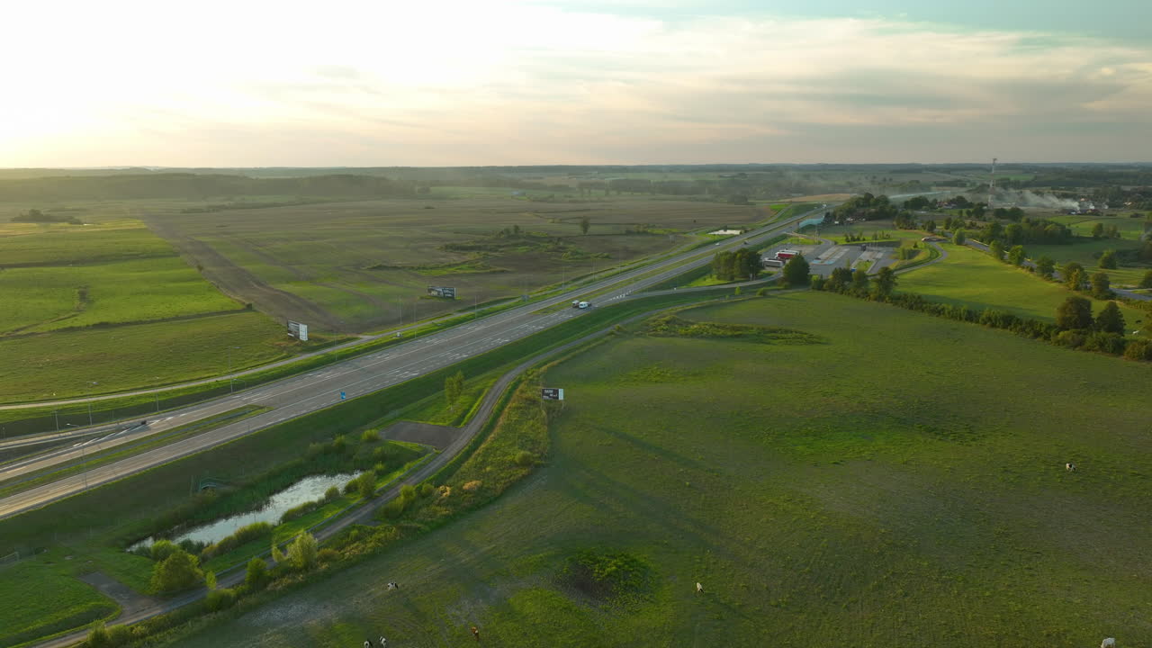 해가 지는 초록색 을 가로질러 구부러지는 고속도로의 조용한 공중 풍경