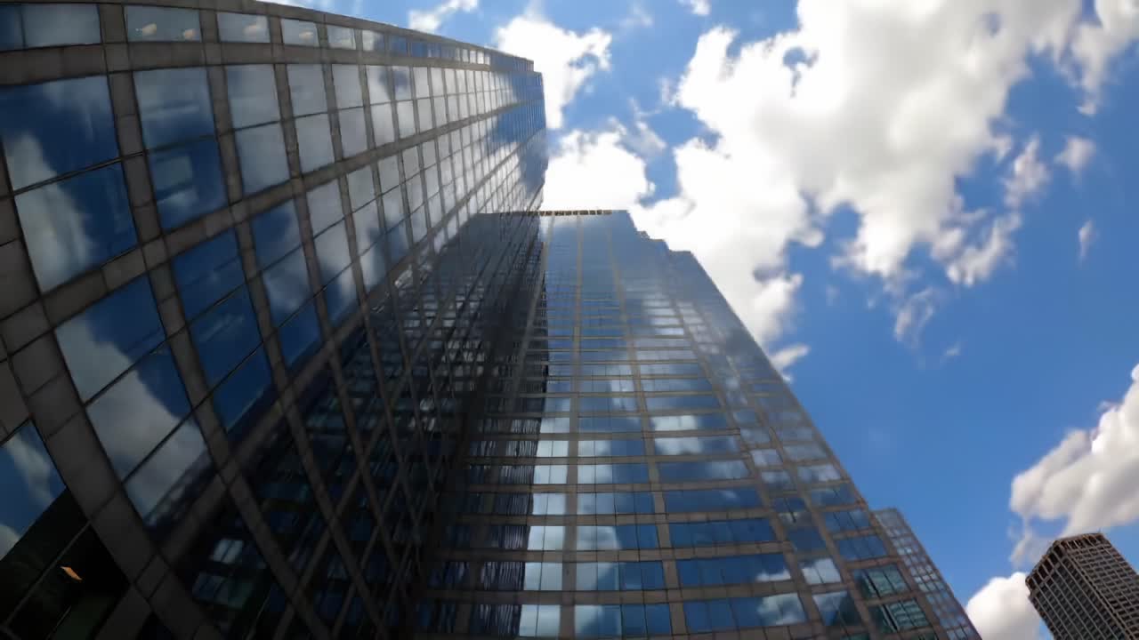 A Dramatic Perspective of a Skyscraper Under a Blue Sky with Clouds: Capturing the Reflection and Height of Modern Architecture in Urban Landscapes