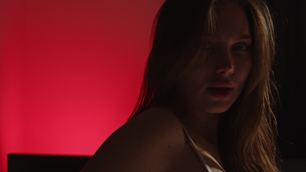 Portrait of an attractive young woman sensually gazing at the camera against a red background