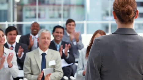 Woman-being-applauded-by-business-people