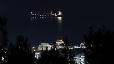 Night-timelapse-of-Thessaloniki-white-tower-ships-go-by-big-ship-background