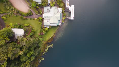 moving drone video looking down on a lush park area next to a volcanic crater lake with boats docked next to pontoon