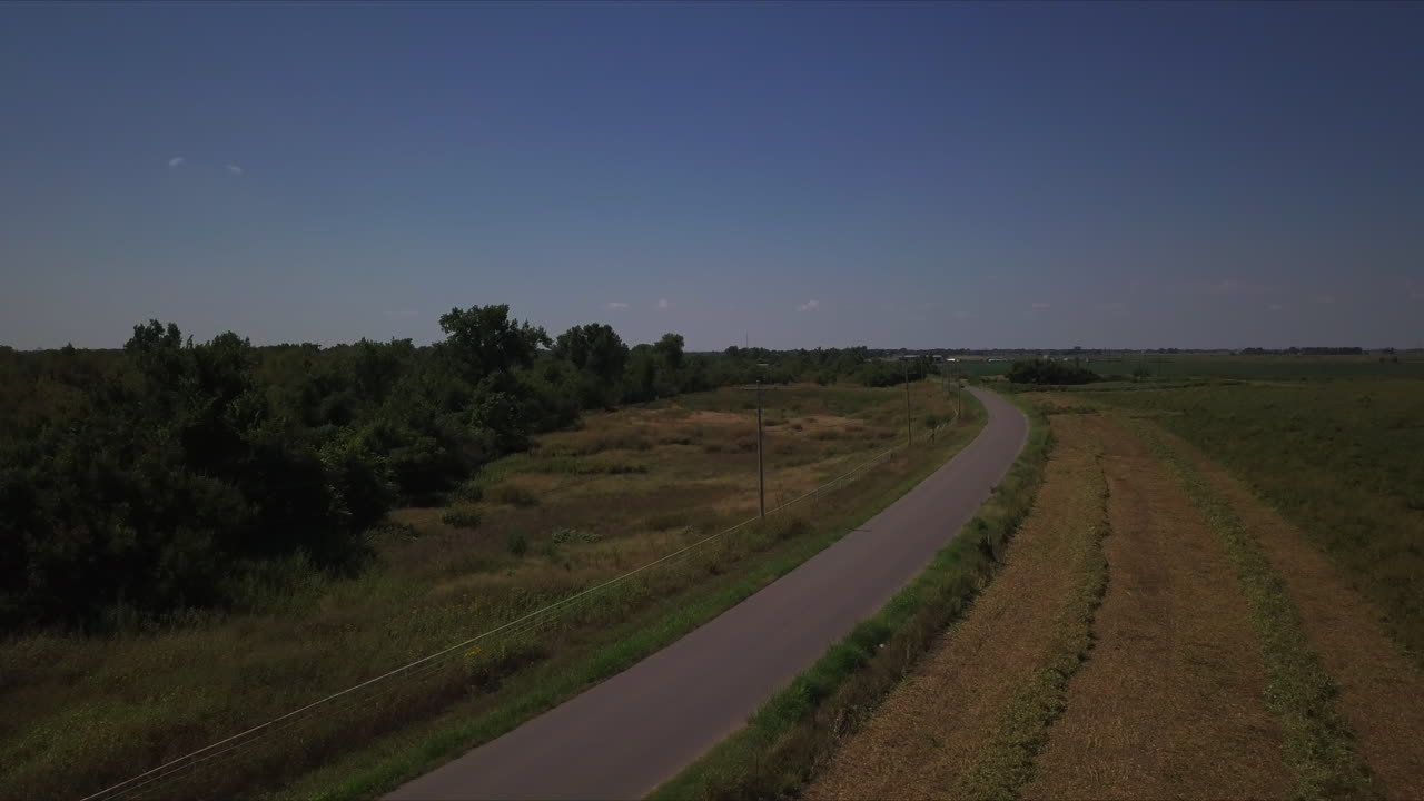 vista aérea que muestra un coche rojo corriendo en una carretera rural con curvas aisladas