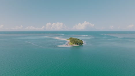 aerial shot - discover of tiny island with forest and no people in the middle of the ocean