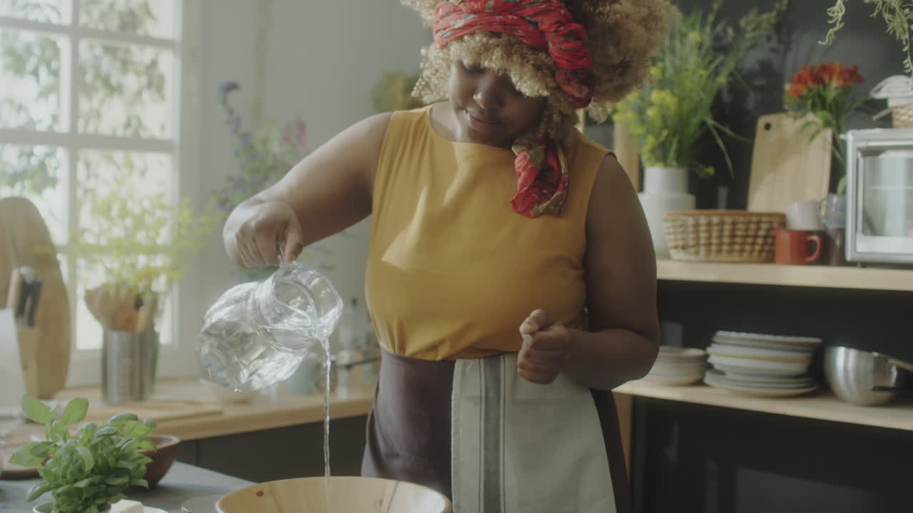 Black Woman Pouring Water in Bowl while Cooking