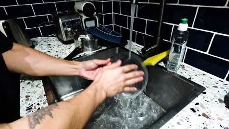 person washing dishes in a kitchen sink