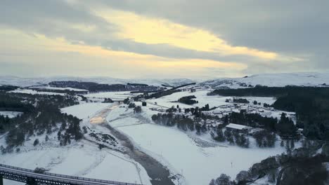 reverse reveal from snow-covered tomatin village along the river to findhorn viaduct