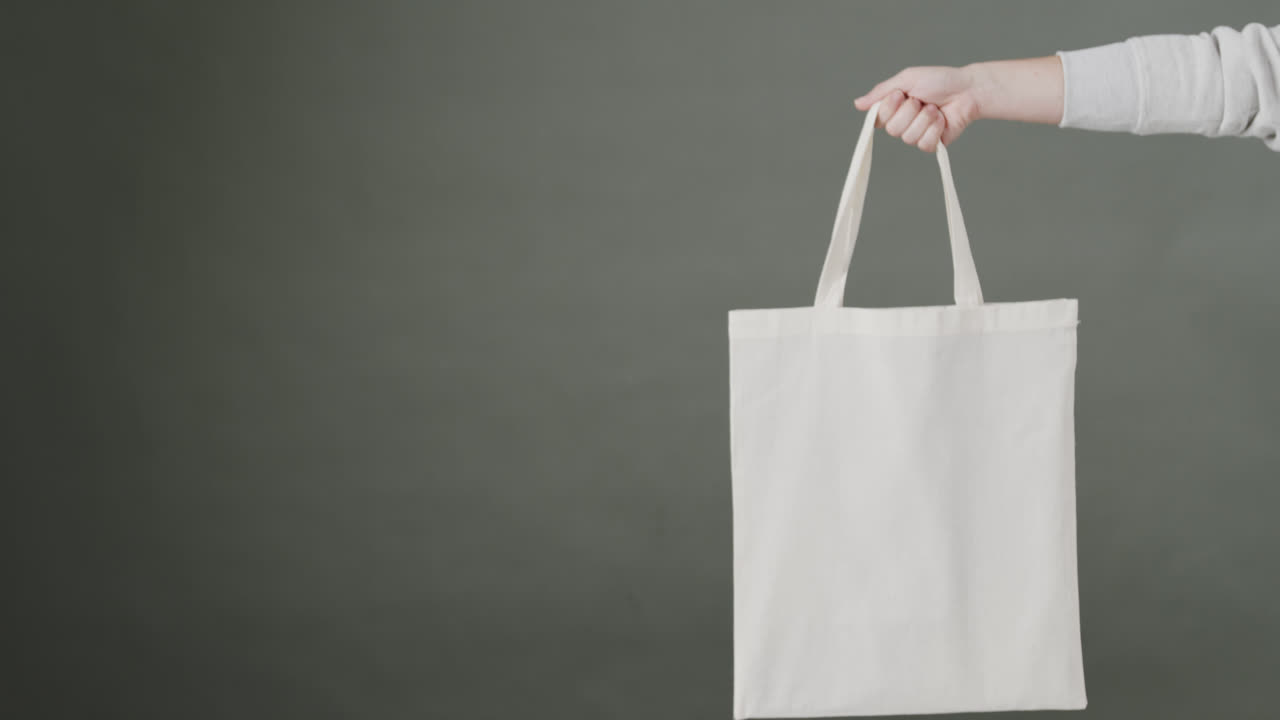 회색 바탕에  가방을 들고 있는 백인 여성의 손, 복사 공간, 느린 동작