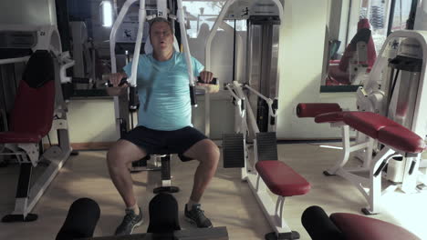 grown man in gym performs exercises chest press