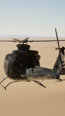 black military helicopter flying over a desert