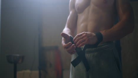 joven atlético caucásico cambiando poniendo correas de levantamiento de pesas en el vestuario del gimnasio antes del entrenamiento cámara lenta. ata los brazos a la barra con correas de fitness.