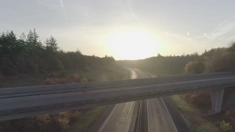 Mountainbiker,-Der-Bei-Sonnenaufgang-Oder-Sonnenuntergang-über-Die-Überführung-Fährt