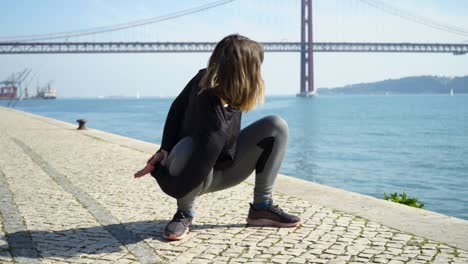 beautiful sporty young woman stretching on embankment