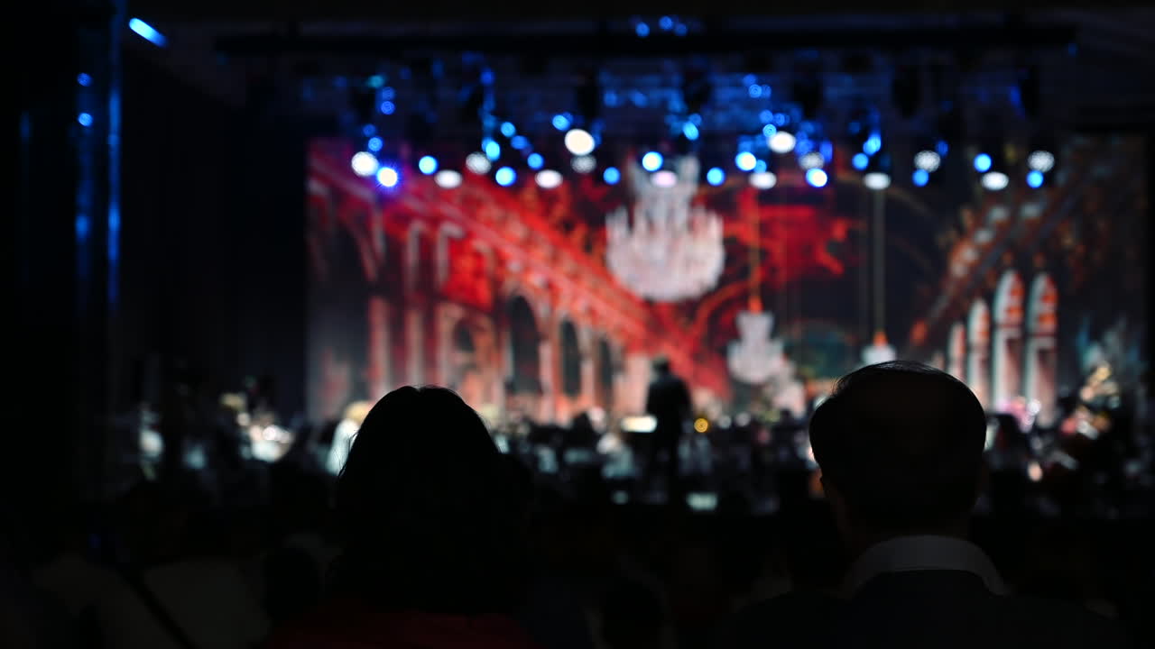 An audience watches a captivating concert featuring live music and impressive light displays. The atmosphere is vibrant and filled with excitement as performers engage the crowd