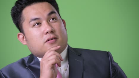 초록색 배경에 젊은 잘생긴 과체중 아시아 사업가