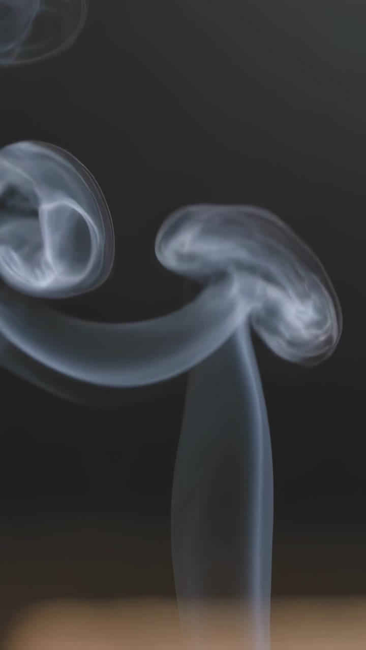 Vertical video: Rising smoke plumes and vortex rings forming above dark edge, showing turbulence