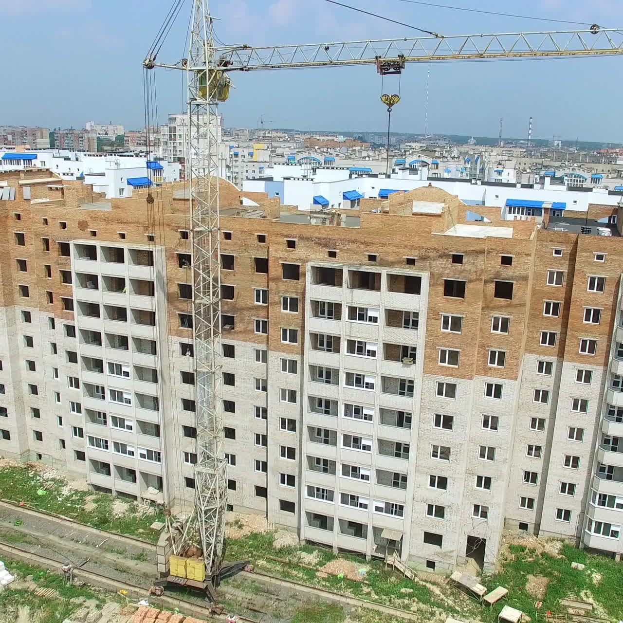 Building construction of the modern residential complex with two cranes near the multy-storey in a sunny day. New house is building in a city. Motion top down.