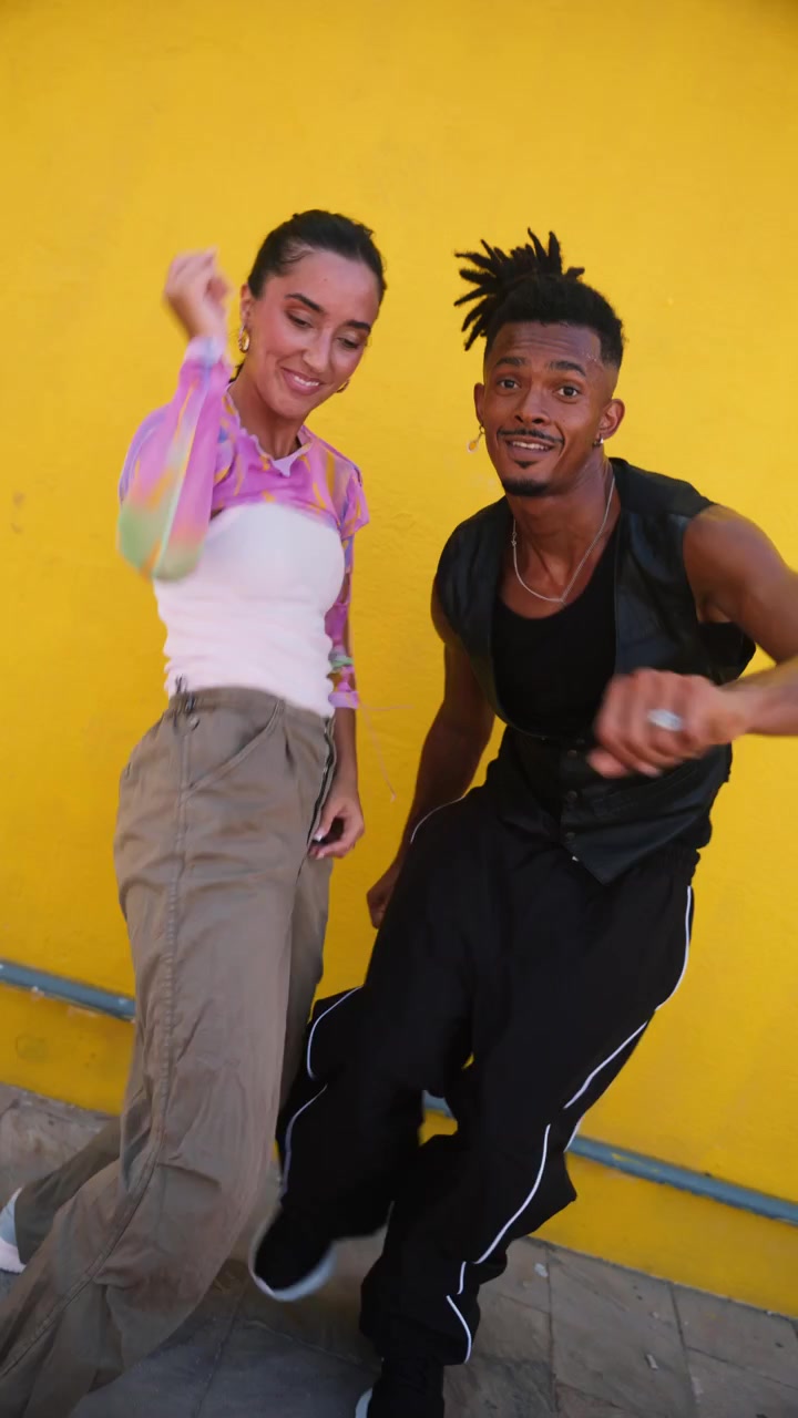 Young Couple Dancing Together Against a Bright Yellow Wall