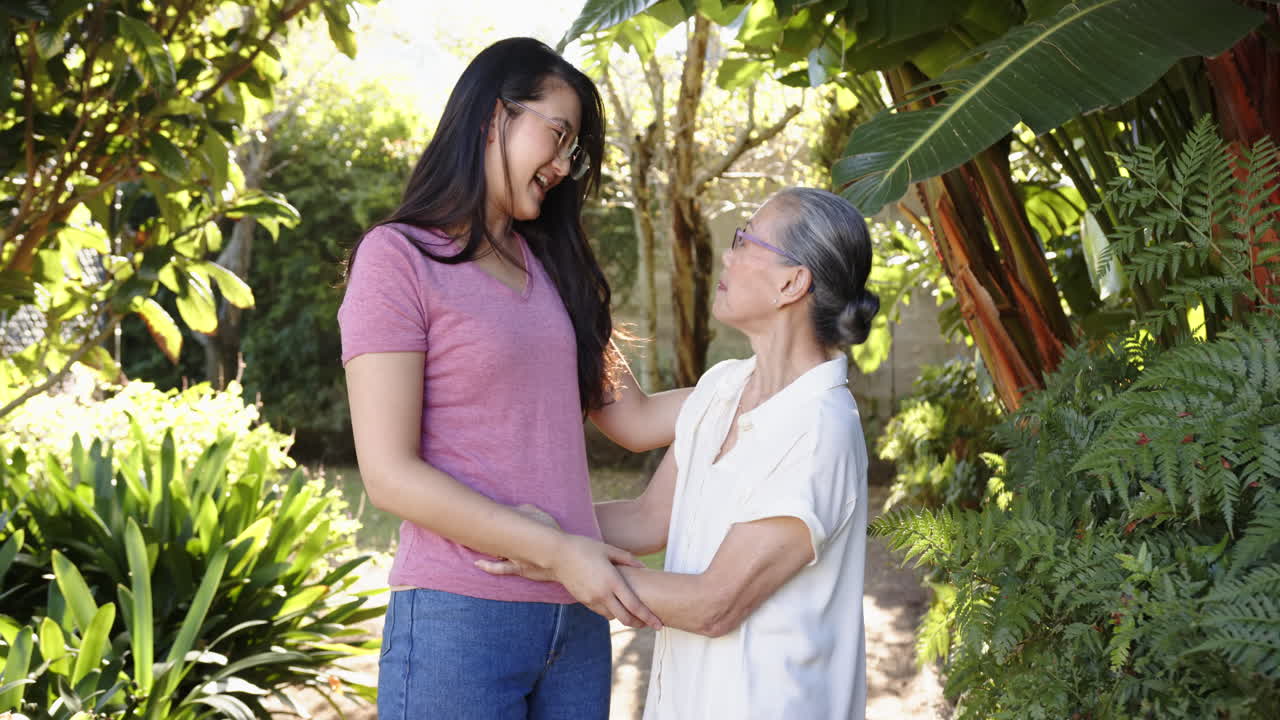 Smiling grandmother and granddaughter bonding together in lush garden setting