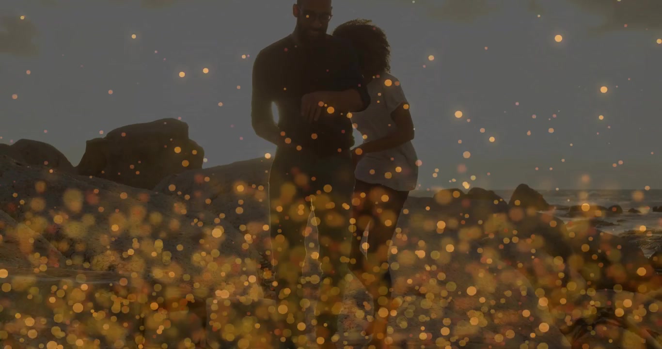 Coppia che si abbraccia sulla spiaggia al tramonto con effetti di luce bokeh