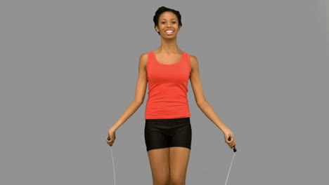 cheerful woman working out with a rope on grey screen