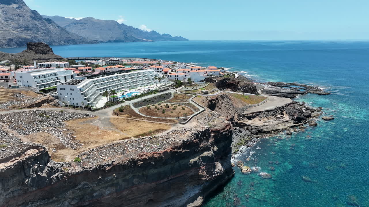 fantástica toma aérea en órbita sobre los edificios en la costa del puerto de agaete en un día soleado y la isla de gran canaria