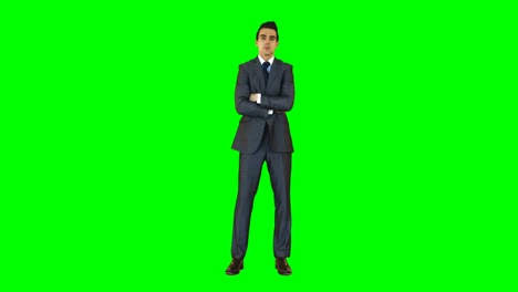 businessman standing with arms crossed against green background