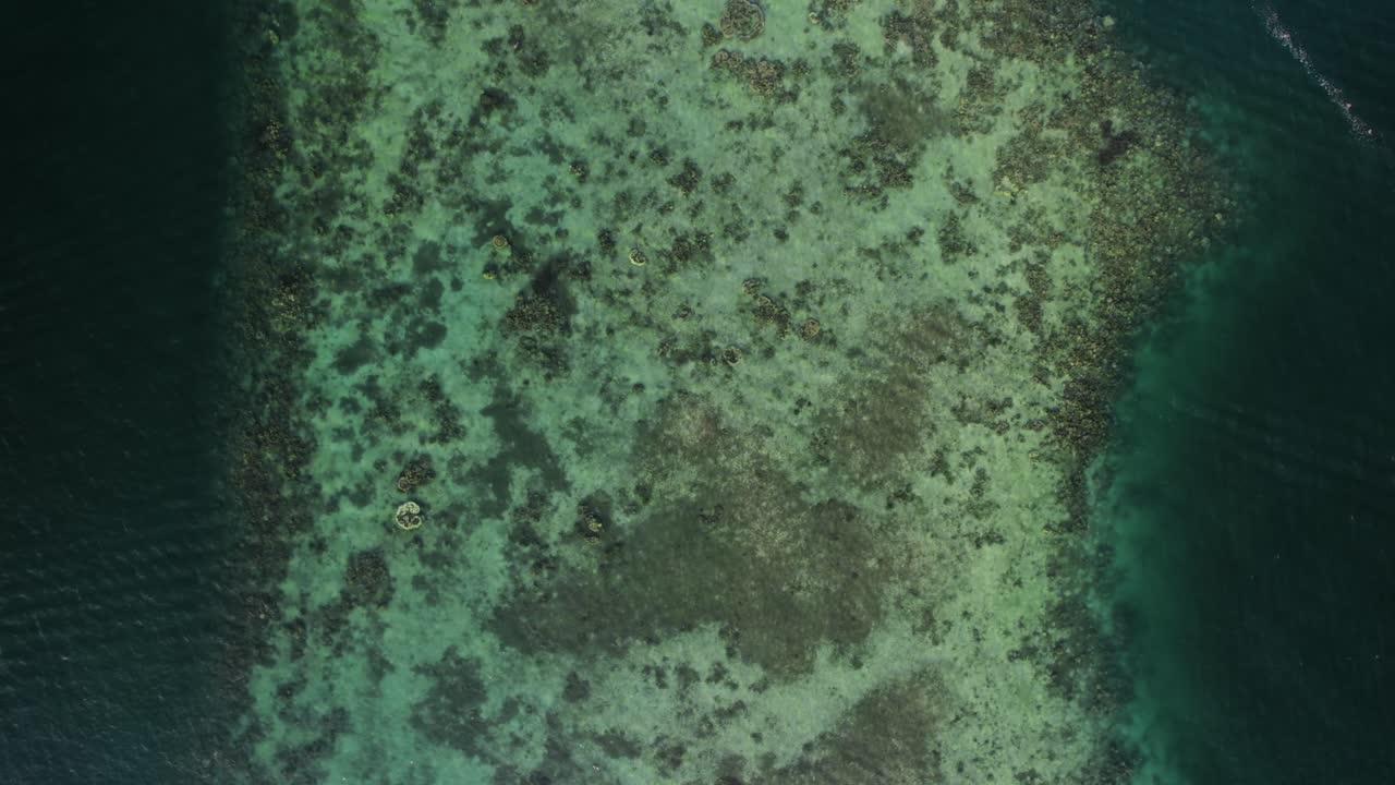 una vista de arriba hacia abajo de una isla en las filipinas, mostrando aguas poco profundas y claras de color turquesa