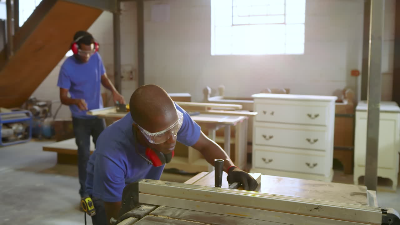 African American man positioning plank at shop table saw cutting with push block for fine boards