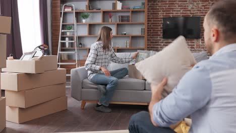 young couple unpacking cardboard box and discussing interior design in new apartment on moving day. happy homeowners on relocation day. real estate and tenancy concept. loan mortgage for young family.