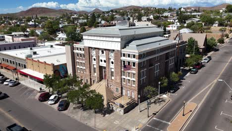 courthouse in downtown globe, arizona. cars driving down street, american flag blowing in wind, partly cloudy day in late july, aerial view