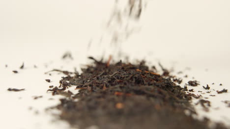 close-up shot of black tea falling on white ground in 100 fps