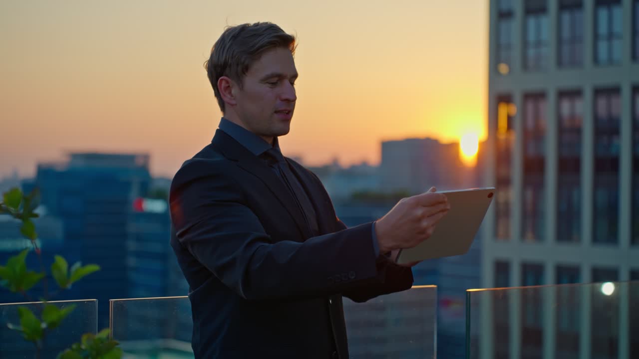 A Caucasian businessman in a suit gestures while presenting information on a tablet, with the modern cityscape of Seoul, South Korea, visible at sunset from a rooftop