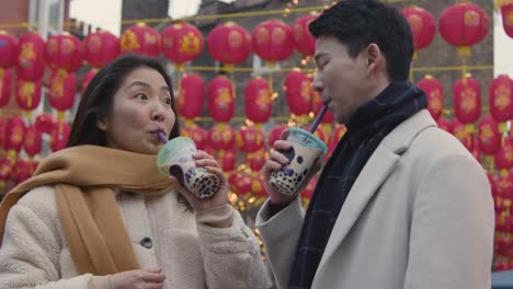 young asian couple on holiday drinking bubble tea in chinatown london uk 4