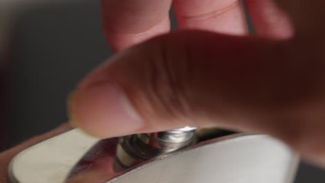 opening uncap the top cap of silver hip flask by hand, close up