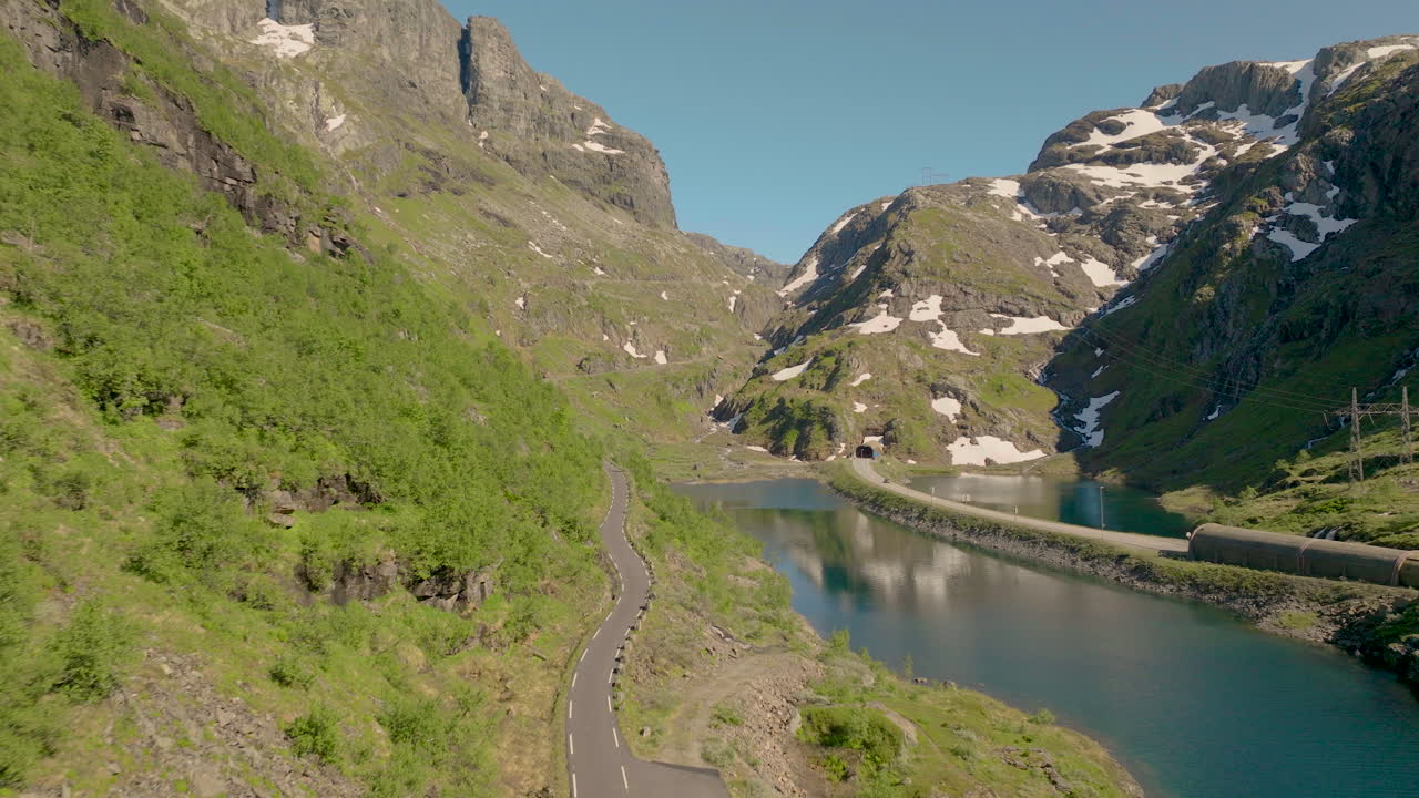paso de montaña a lo largo de un lago tranquilo cerca de la carretera del túnel en verano en el condado de hordaland, noruega