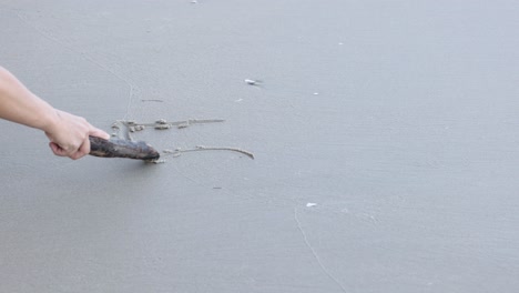 creating art on beach sand using a piece of wood