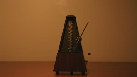 Metronome-that-is-moving-back-and-forth-that-is-it-above-by-a-light-that-is-following-the-swinging-pendulum