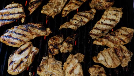 chicken being perfectly charred or char grilled on electric grill with red heating element flames during summer barbecue, as camera quickly pans over meat and out