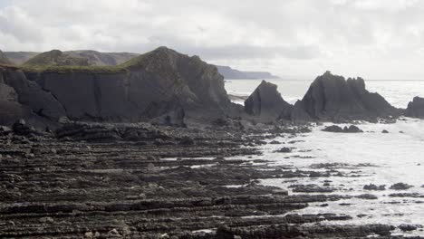 Extra-wide-shot-of-waves-rolling-onto-sedimentary-rocks-at-Hartland-Quay,-Stoke,-Hartland,-Bideford