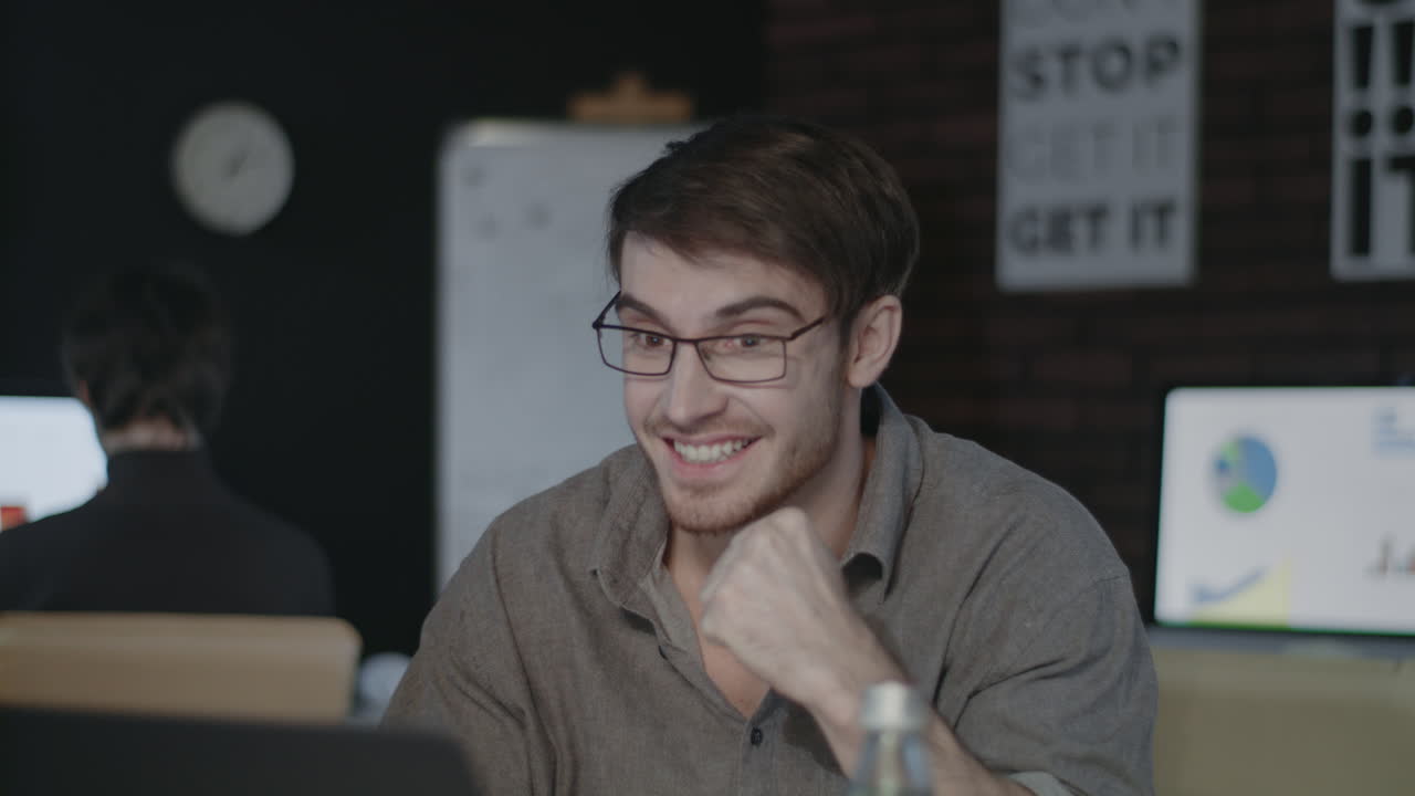 hombre de negocios alegre mirando la pantalla de la computadora portátil y haciendo un gesto de sí en la oficina oscura