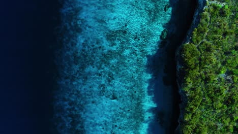 tiefblaues wasser führt zum inneren riff am felsrand einer tropischen insel.